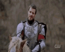 a man in armor is riding a horse in a field .