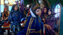 a group of women are standing in a room and one of them is wearing a crown and a blue jacket .