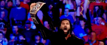 a man is holding a championship belt in front of a crowd .