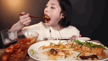 a woman is eating a large plate of food with chopsticks ..