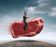a man is riding a giant piece of meat in the air .