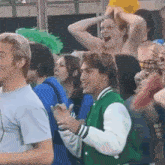 a man in a green jacket is standing in a crowd of people .