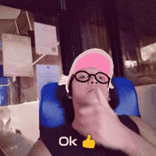 a man wearing a pink hat and glasses is giving a thumbs up