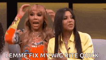 two women are sitting next to each other on a stage and one of them is holding her hair .