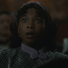 a woman wearing a headband and earrings looks surprised in a dark room