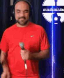 a man in a red shirt is holding a microphone