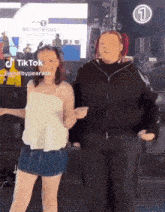 two women are dancing in front of a large screen with the number 1 on it