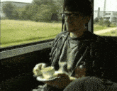 a man wearing glasses is holding a cup of coffee in his hand