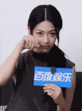 a woman holds a blue sign with chinese characters