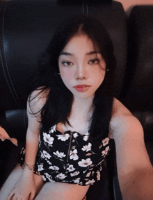 a woman in a black and white floral dress is sitting on a black couch