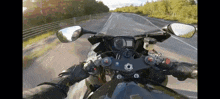 a person riding a motorcycle on a road with trees in the background