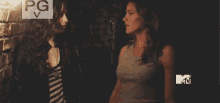 two women are standing next to each other in a dark room with a mtv logo on the bottom right