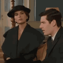 a man and a woman are sitting next to each other and the woman is wearing a black hat
