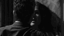 a black and white photo of a man and woman kissing .