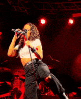 a woman is singing into a microphone on stage