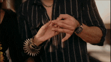 a man wearing a striped shirt is holding a woman 's hand