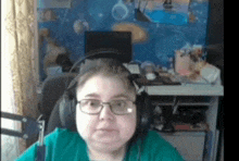 a woman wearing headphones and glasses is sitting in front of a computer .