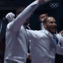 a group of men are standing next to each other with their arms up in the air .