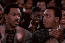 two men are clapping their hands in a crowded room