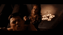 a woman is standing next to a man in a dark room with a light that says 666 on it