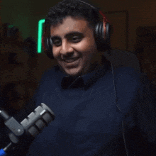 a man wearing headphones stands in front of a rode microphone