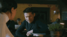 a man and a woman are sitting at a table in a dark room .