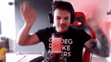 a man wearing headphones is sitting in front of a microphone and waving his hand .