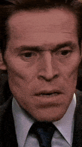 a close up of a man 's face wearing a suit and tie .