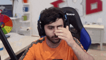 a man wearing headphones is sitting in a gaming chair and cleaning his nose .