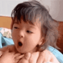 a baby is yawning with his mouth open while being held by a person .
