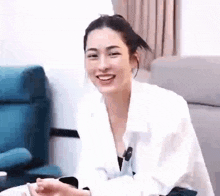 a woman in a white shirt is smiling while sitting in a chair .