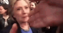 a blurry picture of a woman talking into a microphone while standing in a crowd .