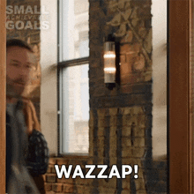 a man standing in front of a window with the word wazzap written on it