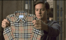 a man holds up a plaid shirt that says burberry