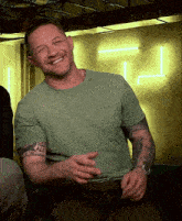 a man in a green shirt has a tattoo on his arm that says " i 'm all bellissime "