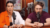 a man and a woman sit in front of microphones
