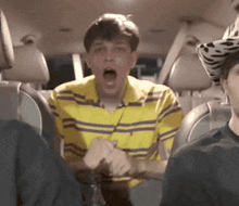 a man in a yellow and purple striped shirt is sitting in the back seat of a car
