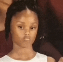 a young girl is making a funny face while sitting down .
