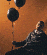 a man holding a bunch of black balloons in his hand