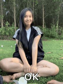 a girl is sitting on the grass with her legs crossed and the word ok is on the bottom
