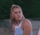 a woman in a blue and white tank top is looking up