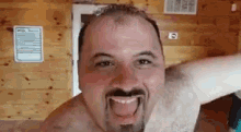 a shirtless man with a beard and mustache is making a funny face with his tongue out .