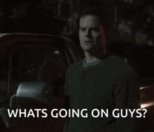 a man standing in front of a car with the words " whats going on guys " written below him