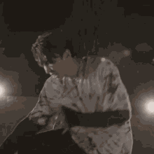 a man wearing a tie dye shirt is standing in front of a light .