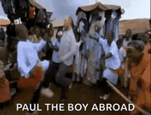 a group of people are dancing in front of a sign that says paul the boy abroad ..
