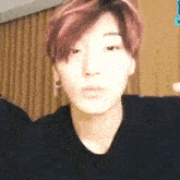 a close up of a person 's face with red hair , earrings and a black shirt .