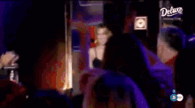 a group of people are dancing in front of a sign that says " deluxe "