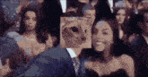 a man in a suit and tie stands in front of a crowd of people with a picture of a cat on his face
