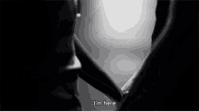a black and white photo of two people holding hands with the words `` i 'm here '' written on the bottom .