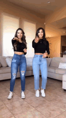 two women are dancing in front of a couch with a sign that says love on it
